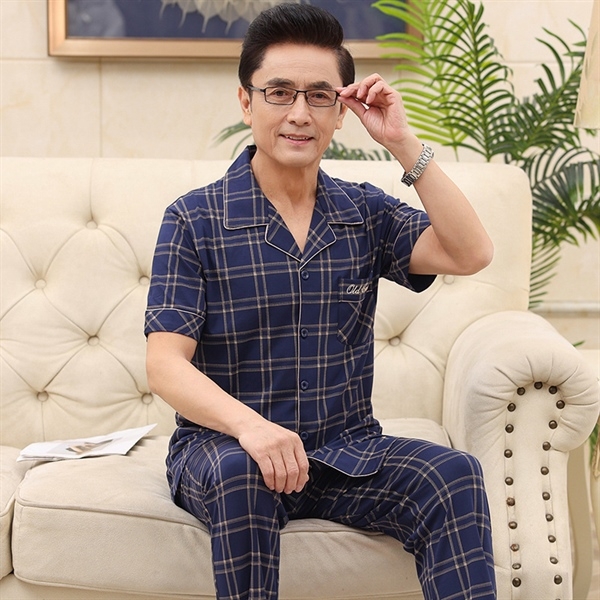 Bộ đồ ngủ nam trung niên kẻ caro xanh navy tay ngắn quần dài ngồi trên ghế sofa