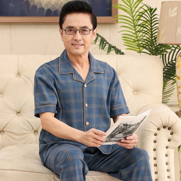 Bộ đồ ngủ nam trung niên kẻ caro xanh ngồi trên sofa cầm tạp chí