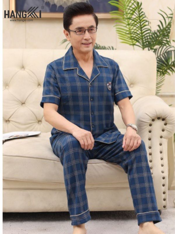 Bộ đồ ngủ nam trung niên kẻ caro xanh navy tay ngắn quần dài ngồi trên ghế sofa