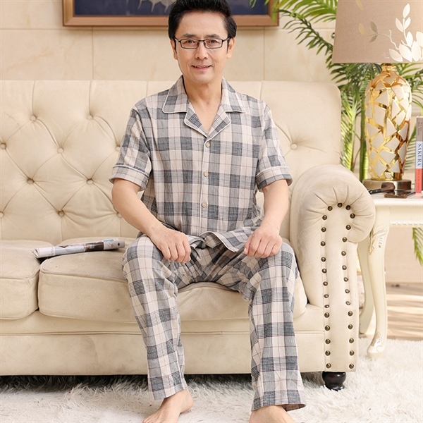Bộ đồ ngủ nam trung niên kẻ caro tay ngắn quần dài màu be xám ngồi trên ghế sofa
