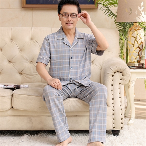 Bộ đồ ngủ nam trung niên kẻ caro màu xám tay ngắn quần dài ngồi trên ghế sofa