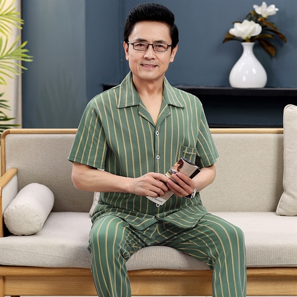 Bộ đồ ngủ nam trung niên kẻ sọc xanh ngồi trên ghế sofa trong phòng khách