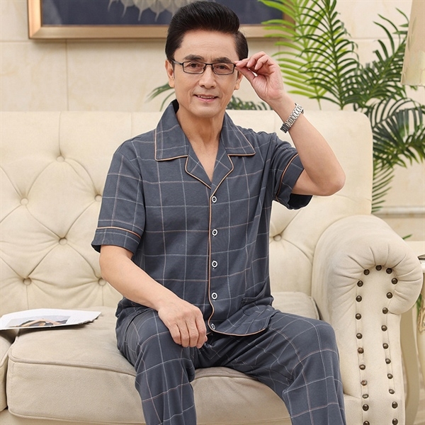 Bộ đồ ngủ nam trung niên kẻ caro màu xám tay ngắn quần dài ngồi trên ghế sofa
