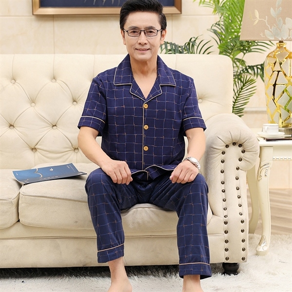 Bộ đồ ngủ nam trung niên màu xanh navy kẻ caro ngồi trên ghế sofa trong phòng khách