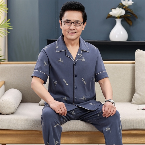Bộ đồ ngủ nam trung niên màu xanh xám tay ngắn quần dài họa tiết nhỏ ngồi trên ghế sofa