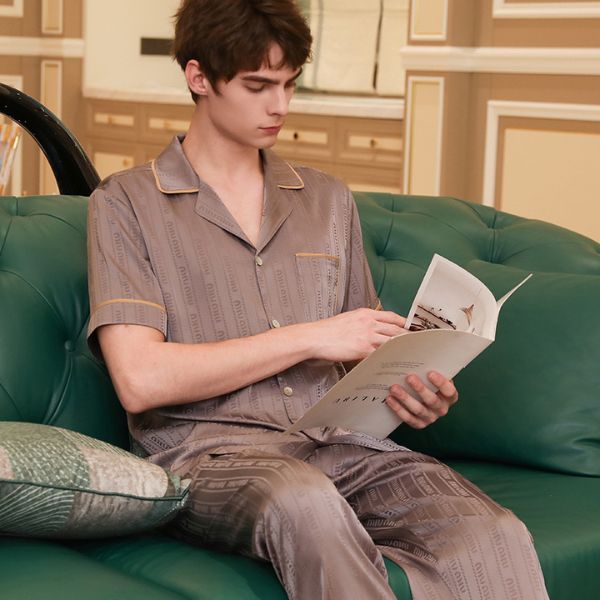 Nam giới mặc bộ pijama lụa màu nâu nhạt tay ngắn quần dài ngồi đọc tạp chí trên ghế sofa xanh