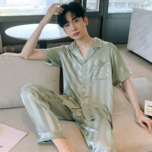 Nam giới mặc bộ pijama lụa kẻ sọc màu xanh nhạt ngồi trên ghế sofa trong phòng khách