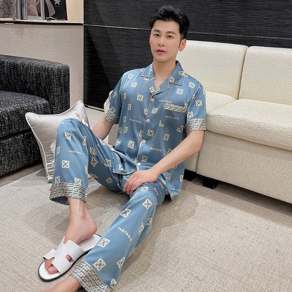 Đồ ngủ lụa nam màu xanh họa tiết chữ, tay ngắn quần dài, người mẫu ngồi trên sàn cạnh sofa