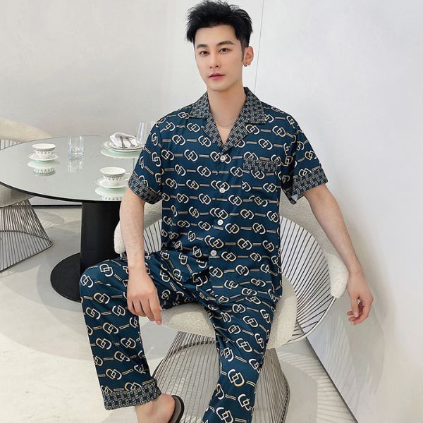 Bộ đồ ngủ nam lụa màu xanh đậm họa tiết mắt xích vàng tay ngắn quần dài ngồi trên ghế trong phòng khách
