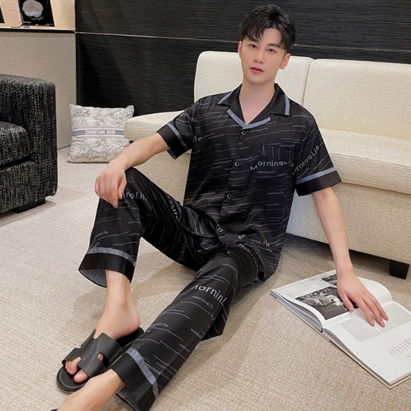 Nam giới mặc bộ pijama lụa đen tay ngắn quần dài họa tiết chữ ngồi thư giãn trong phòng khách