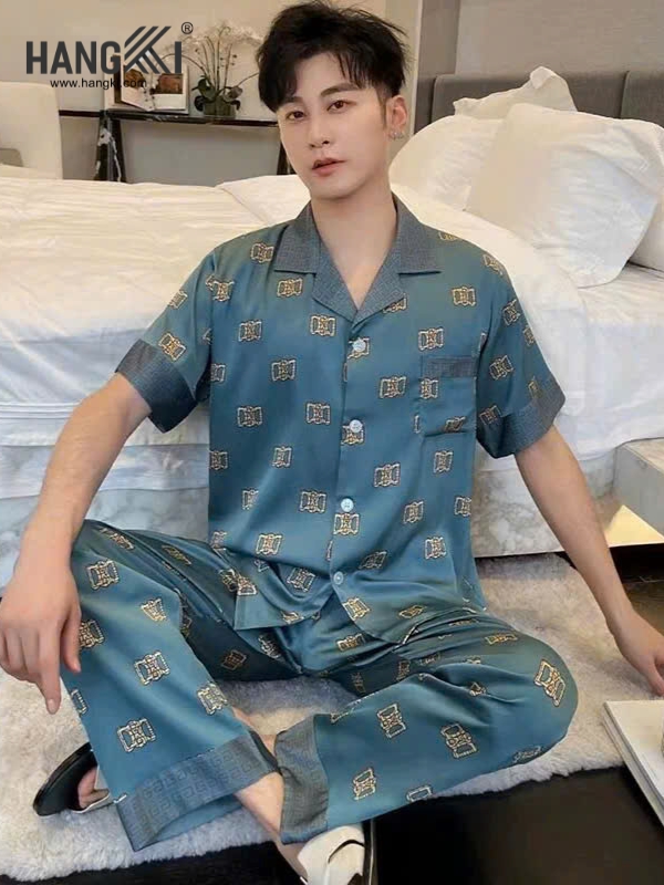 Bộ pijama lụa nam màu xanh họa tiết ngồi trên giường trong phòng ngủ hiện đại