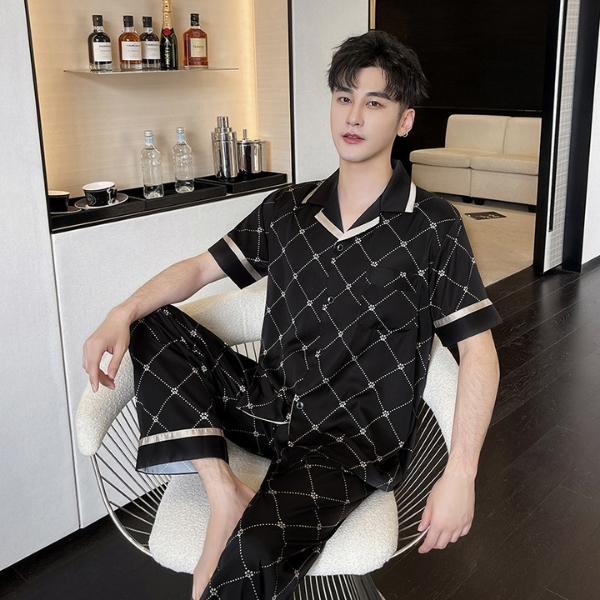Bộ pijama lụa nam màu đen họa tiết caro trắng tay ngắn quần dài ngồi trên ghế trong phòng khách