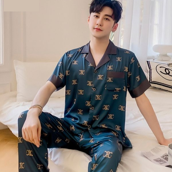 Bộ pijama lụa nam màu xanh đậm họa tiết vàng tay ngắn quần dài ngồi trên giường ngủ