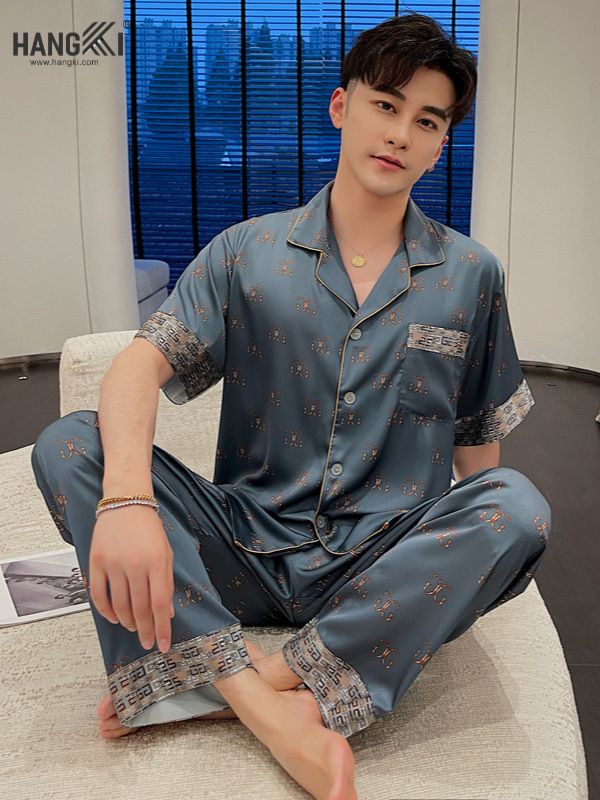 Nam giới mặc bộ pijama lụa xanh họa tiết sang trọng ngồi trên sofa trong phòng khách hiện đại