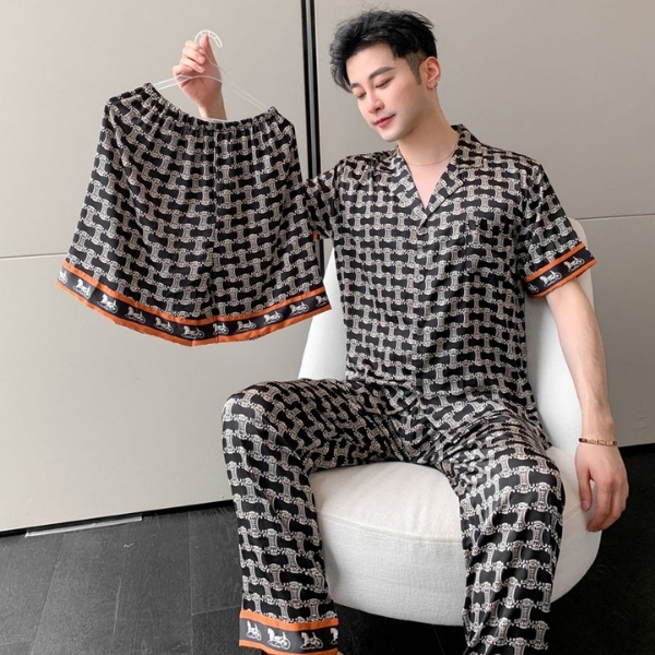 Bộ đồ ngủ lụa nam họa tiết đen trắng viền cam, người mẫu ngồi ghế cầm thêm quần đùi cùng bộ