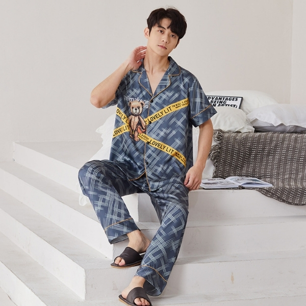 Nam giới mặc bộ pijama kẻ caro xanh in gấu bông ngồi trên bậc thang trong phòng ngủ