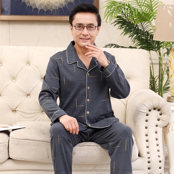 Bộ đồ ngủ nam trung niên màu xám dài tay quần dài họa tiết đơn giản ngồi trên ghế sofa