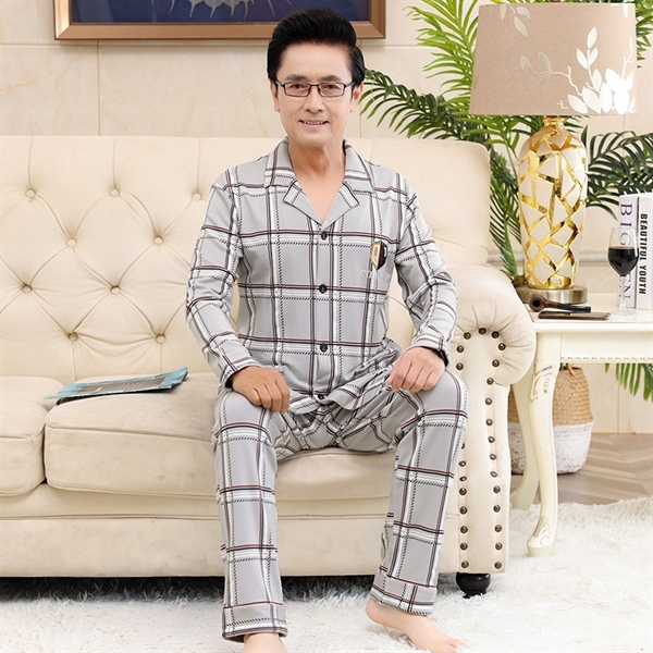 Bộ đồ ngủ nam trung niên kẻ caro dài tay màu xám ngồi trên ghế sofa trong phòng khách