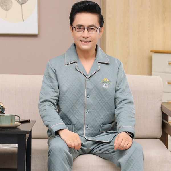 Bộ đồ ngủ nam trung niên màu xanh nhạt chất liệu chần bông ngồi trên ghế sofa