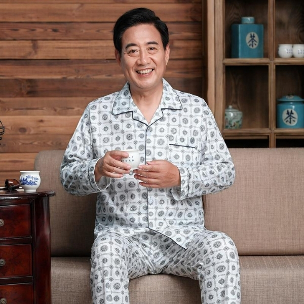 Bộ pijama nam trung niên dài tay quần dài họa tiết tròn màu trắng xám ngồi trên sofa uống trà