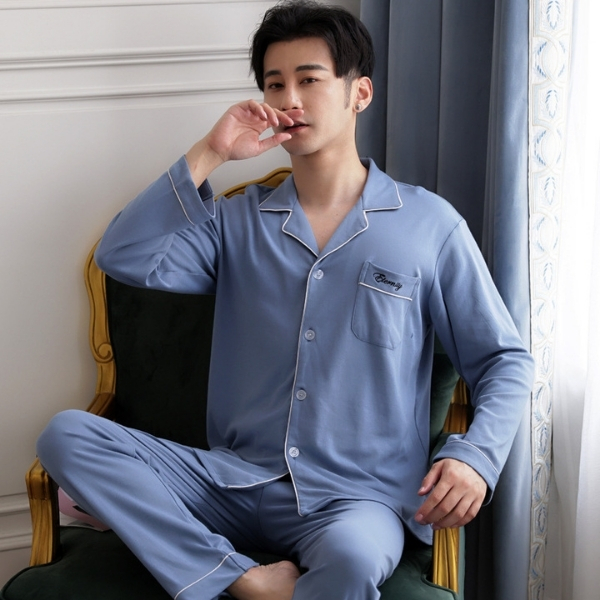 Bộ pijama dài tay màu xanh lam cho nam chất vải mềm mại ngồi trên ghế cạnh rèm cửa