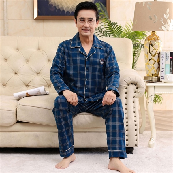 Bộ đồ ngủ nam trung niên kẻ caro xanh dài tay quần dài ngồi trên ghế sofa trong phòng khách