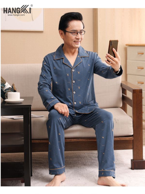 Bộ pijama nam trung niên màu xanh dài tay quần dài họa tiết nhỏ ngồi trên sofa dùng điện thoại