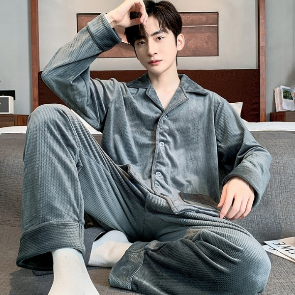 Nam giới mặc bộ pijama vải nhung màu xám ngồi trên giường trong phòng ngủ hiện đại
