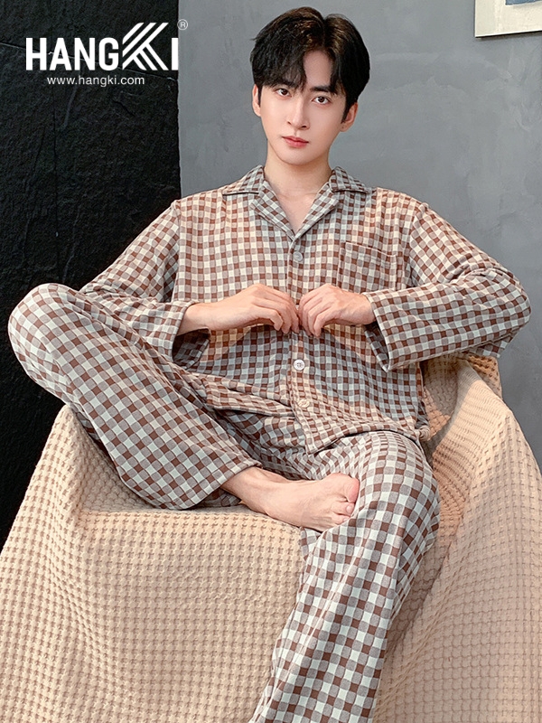 Nam giới mặc bộ pijama kẻ caro dài tay màu nâu be thương hiệu Hangki ngồi trên ghế vải mềm