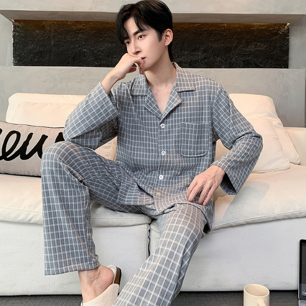 Nam giới mặc bộ pijama dài tay kẻ caro màu xám ngồi trên sofa trong phòng khách