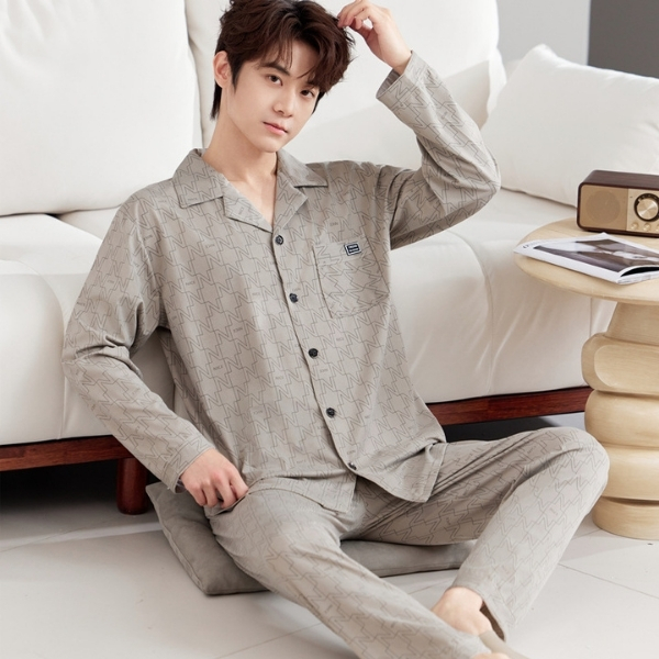 Nam giới mặc bộ pijama dài tay màu be họa tiết đơn giản ngồi trên sàn cạnh sofa trắng