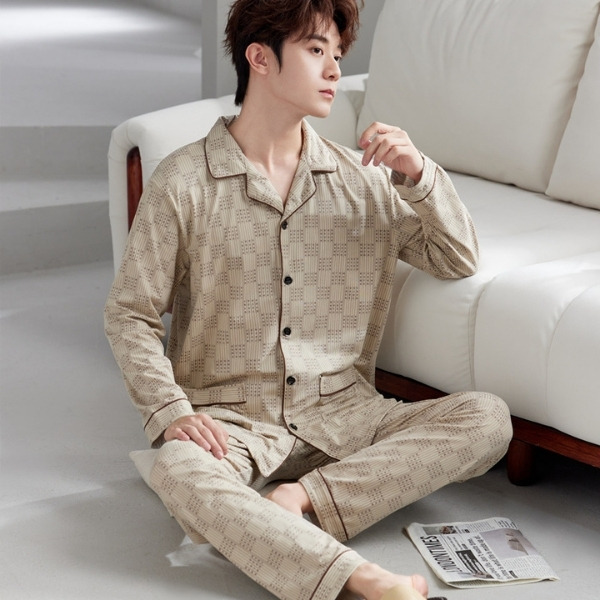 Nam giới mặc bộ pijama dài tay màu be họa tiết ngồi tựa ghế sofa trong phòng ngủ sáng