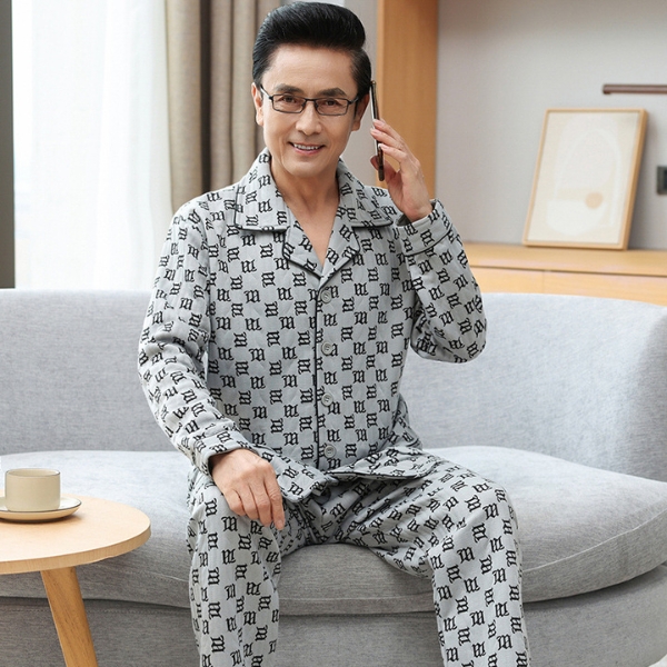 Bộ đồ ngủ nam trung niên màu xám họa tiết chữ ngồi trên sofa trong phòng khách