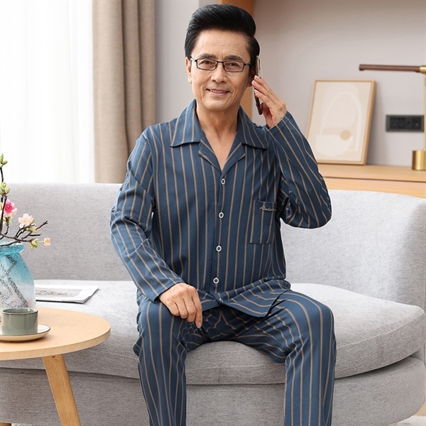 Bộ đồ ngủ nam trung niên kẻ sọc xanh dài tay quần dài ngồi trên sofa cầm điện thoại