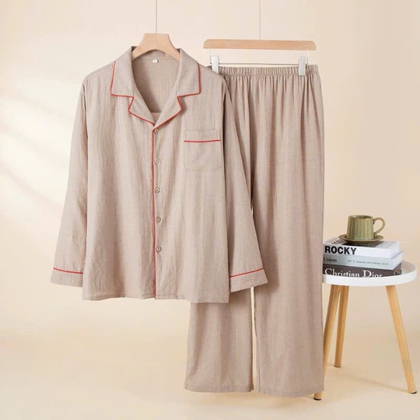 Bộ pijama dài tay màu be viền đỏ treo trên mắc áo cạnh bàn nhỏ có sách và cốc xanh