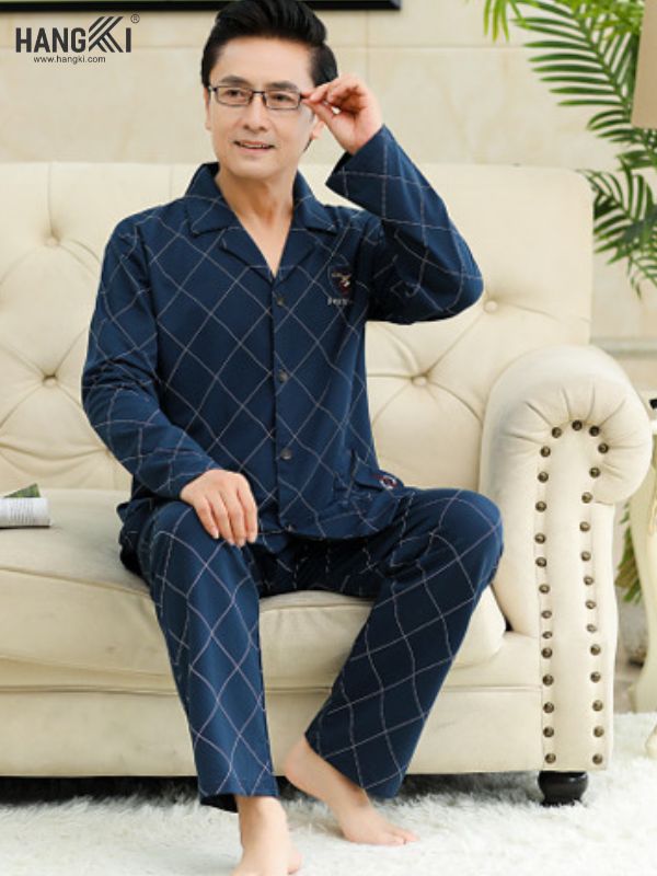 Bộ đồ ngủ nam trung niên màu xanh navy họa tiết caro ngồi trên ghế sofa