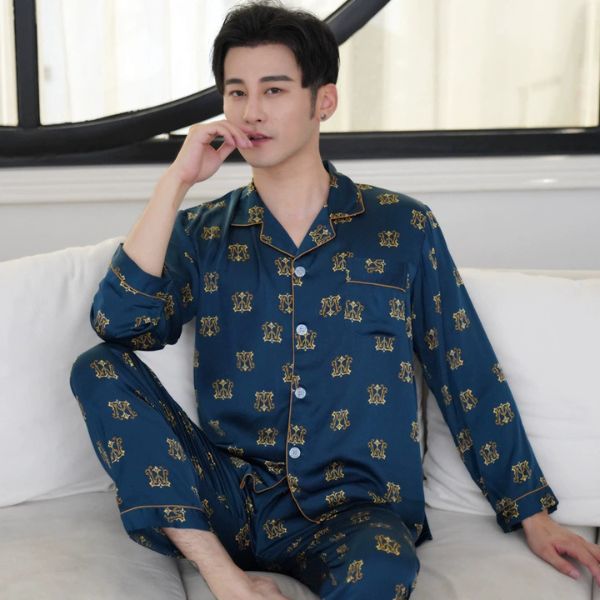 Bộ pijama lụa nam màu xanh đậm họa tiết vàng dài tay quần dài ngồi trên ghế sofa