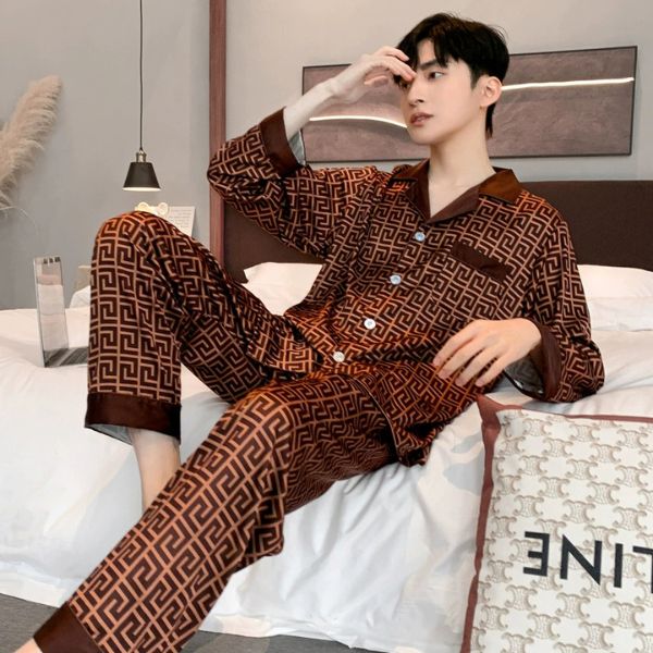 Nam giới mặc bộ pijama lụa dài tay màu nâu họa tiết hình học ngồi trên giường ngủ