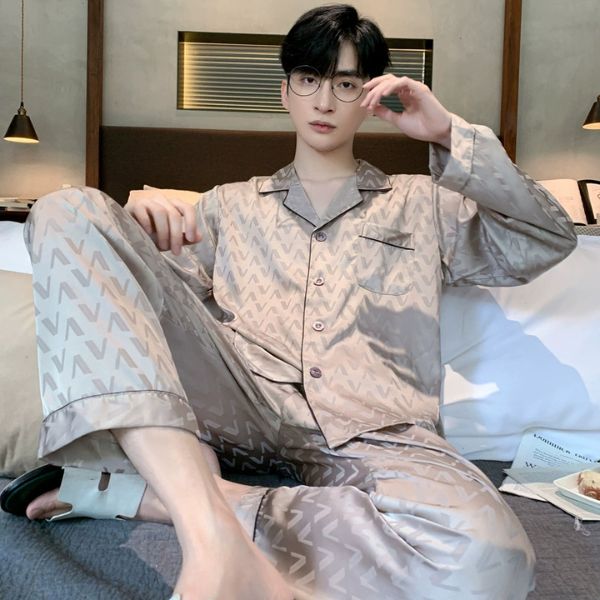 Bộ pijama lụa nam màu be họa tiết chữ V, dáng dài tay quần dài, người mẫu ngồi trên giường