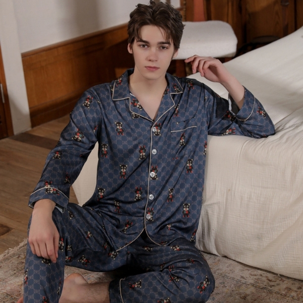 Bộ pijama lụa nam màu xanh họa tiết gấu ngồi cạnh giường trong phòng ngủ