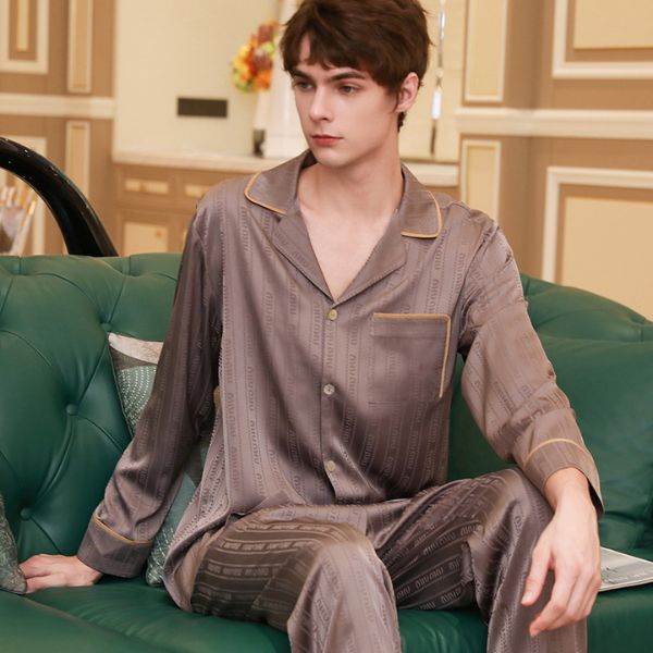 Bộ pijama lụa nam màu nâu xám dài tay quần dài ngồi trên ghế sofa xanh trong phòng khách