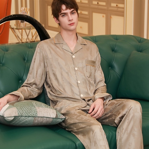 Bộ đồ ngủ lụa nam màu be dài tay quần dài, cổ bẻ, cúc trắng, người mẫu ngồi trên sofa xanh