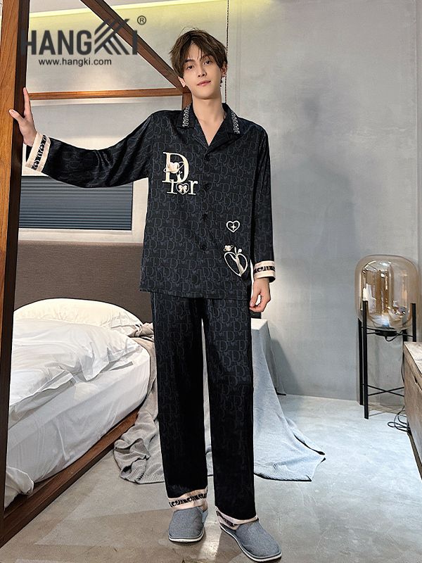 Nam giới mặc bộ pijama lụa màu đen họa tiết chữ Dior đứng trong phòng ngủ hiện đại