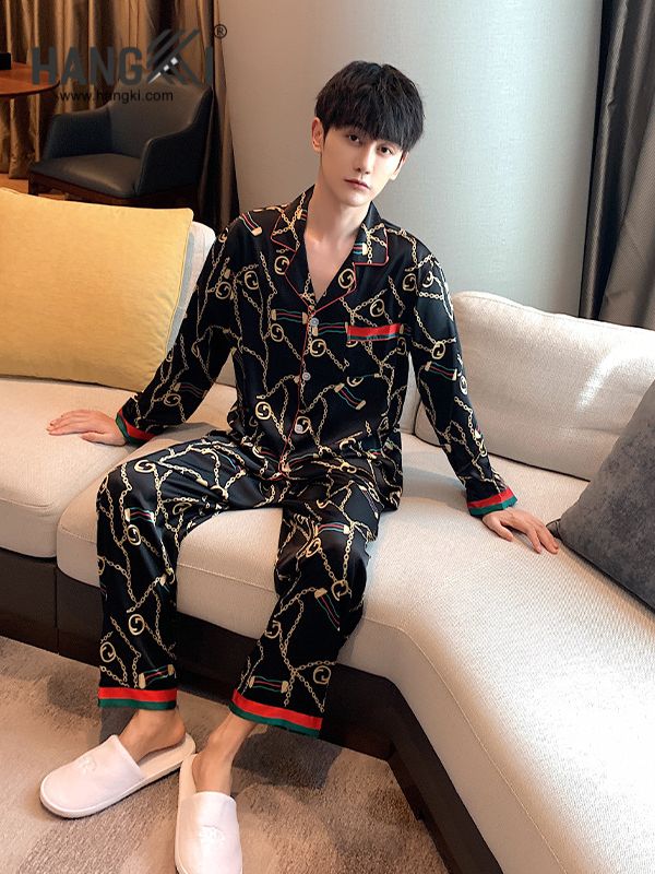 Nam giới mặc bộ pijama lụa đen họa tiết xích vàng viền đỏ xanh ngồi trên sofa trong phòng khách