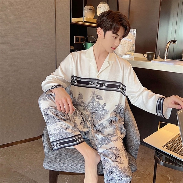 Bộ pijama nam lụa trắng họa tiết phong cảnh, viền chữ CHRISAN DEAR, người mẫu ngồi làm việc bên laptop