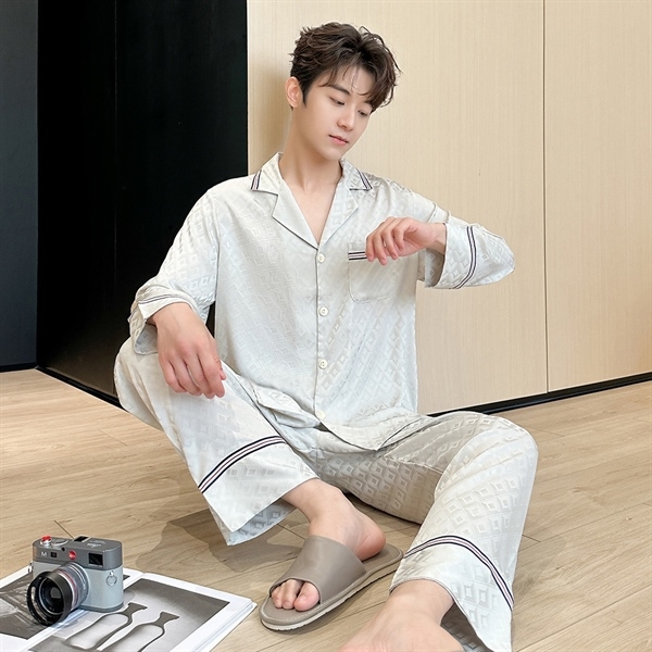 Nam giới mặc bộ pijama lụa màu trắng họa tiết caro ngồi trên sàn gỗ trong phòng ngủ hiện đại
