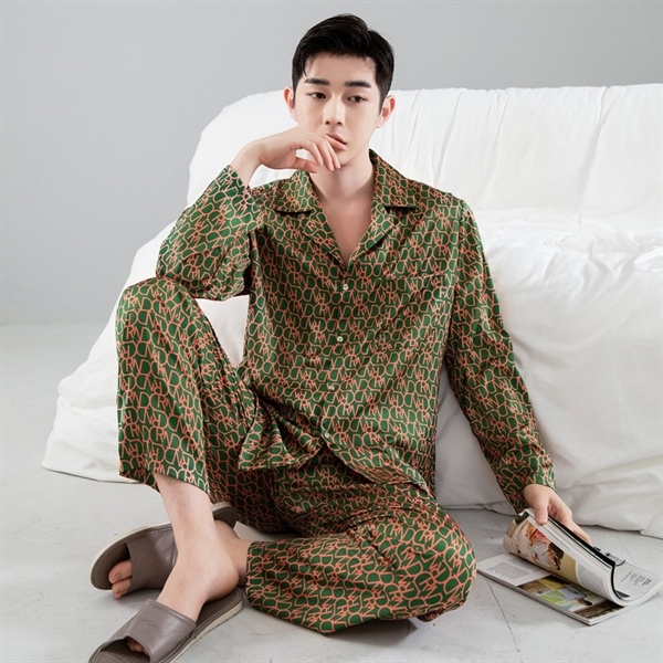 Nam giới mặc bộ pijama lụa dài tay họa tiết xanh nâu ngồi trên sàn cạnh ghế sofa trắng