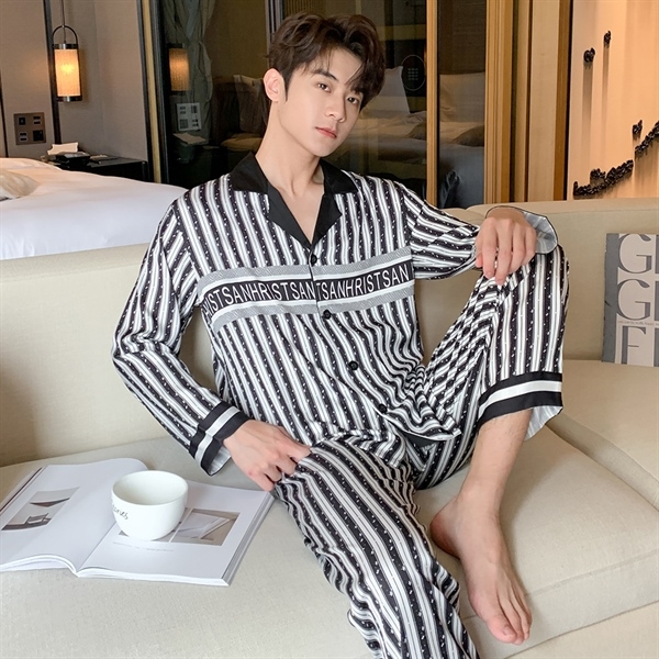 Nam giới mặc bộ pijama lụa dài tay sọc trắng đen ngồi trên ghế sofa trong phòng ngủ hiện đại