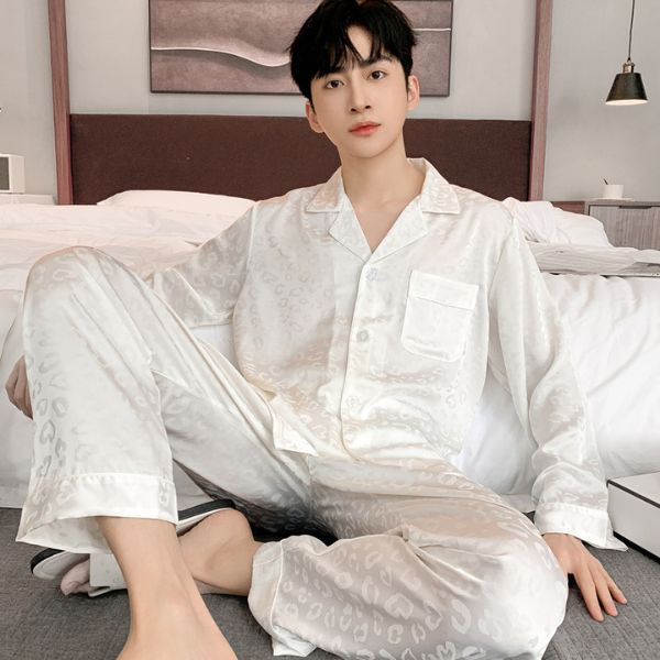 Bộ pijama lụa trắng dài tay cho nam ngồi trên giường trong phòng ngủ hiện đại