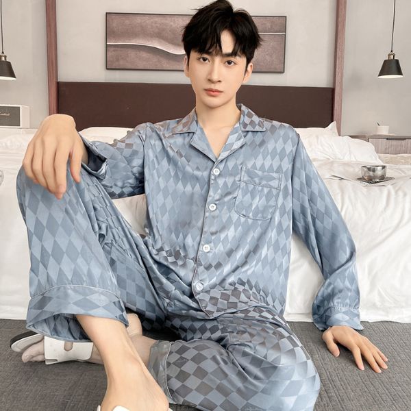 Bộ pijama lụa nam màu xanh xám họa tiết caro ngồi trên giường trong phòng ngủ hiện đại
